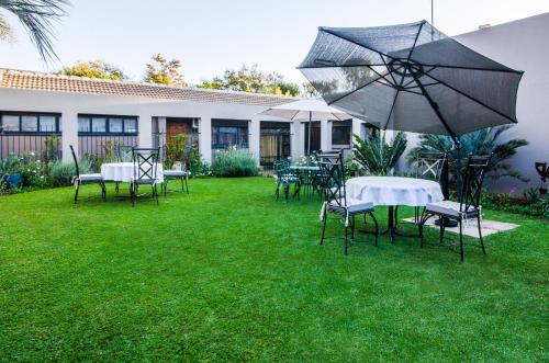 a group of tables and chairs with an umbrella at Three Olives Guesthouse in Centurion