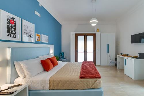 a blue and white bedroom with a bed with red pillows at Anima Rooms Apartments in Sciacca