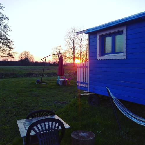 a blue tiny house in a yard with a chair at Les roulottes du Moulin de Palet in Chartrené