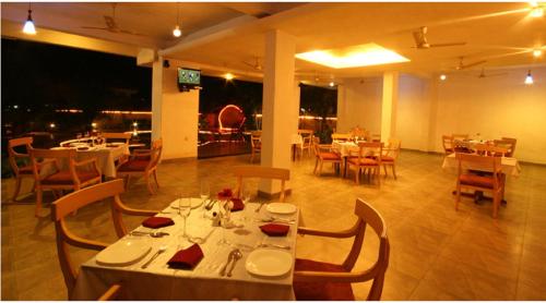 a restaurant with white tables and chairs and tablesearcher at Lambana Resort in Calangute