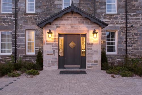 a brick house with a black door and lights at Dunalastair Hotel Suites in Kinloch Rannoch