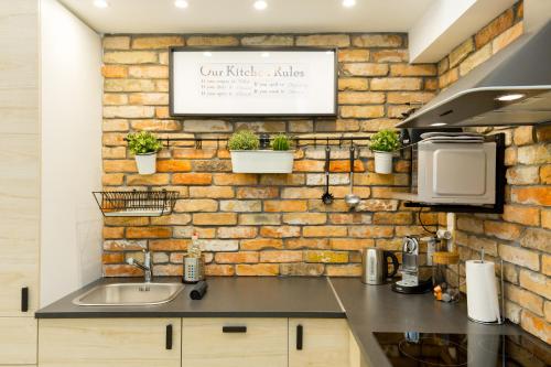a kitchen with a sink and a brick wall at Pastel paradise with a ray of sunshine in Budapest