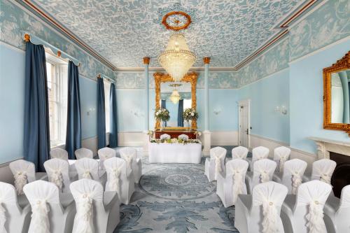 a room with a bunch of chairs and a chandelier at Ensana Buxton Crescent in Buxton