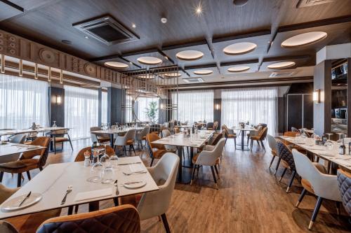 un restaurant avec des tables, des chaises et des fenêtres dans l'établissement Gillieru Harbour Hotel, à San Pawl il-Baħar