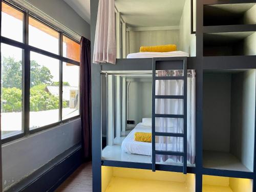 a room with bunk beds with a ladder and a bed at Arch Dormitorio Cenang in Pantai Cenang