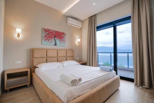 a bedroom with a large bed with a large window at Hotel Roalb in Vlorë