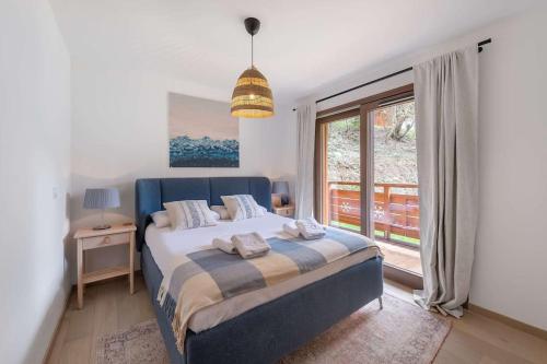 ein Schlafzimmer mit einem Bett und einem großen Fenster in der Unterkunft Quintessence - Apt B202 - BO Immobilier in Châtel