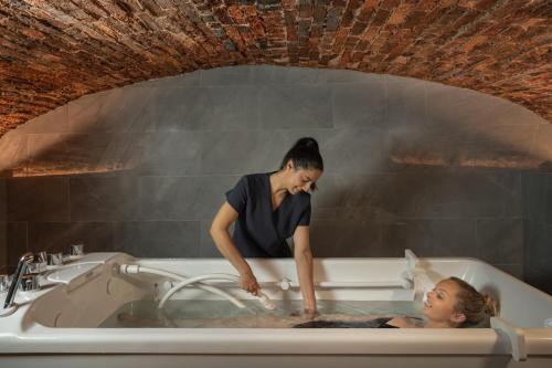 a woman standing in a bath tub with a girl in it at Ensana Buxton Crescent in Buxton