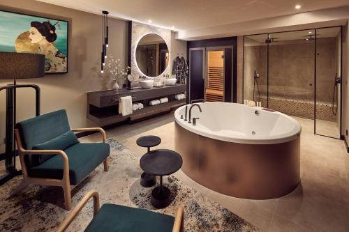 baño grande con bañera grande y silla en Van der Valk Hotel Tiel, en Tiel