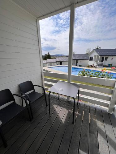 a porch with two chairs and a table and a pool at Domki M&L in Polańczyk