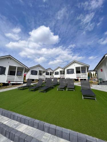 a group of chairs on a lawn in front of houses at Domki M&L in Polańczyk