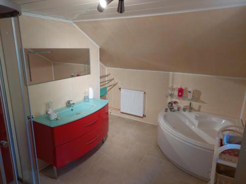 La salle de bains est pourvue d'une baignoire blanche, d'un lavabo et d'une baignoire. dans l'établissement Chambre a proximité du circuit des 24 heures, à Guémardières