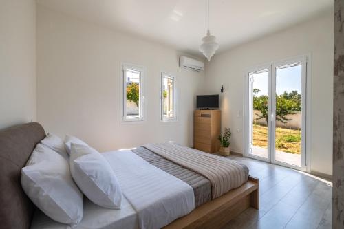 a white bedroom with a bed and two windows at Amy's Seaside Oasis in Argostoli