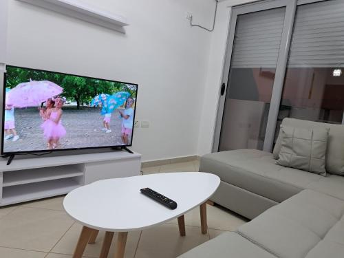 ein Wohnzimmer mit einem TV und einem weißen Tisch in der Unterkunft Bjora Home in Vlorë