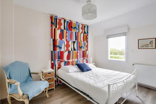 1 dormitorio con 1 cama, 1 silla y 1 cortina en Détente et calme sur la Côte d’Émeraude, en Port Blanc