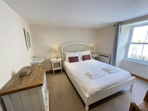 1 dormitorio con cama, escritorio y ventana en Hollies Cottage, en St Ives