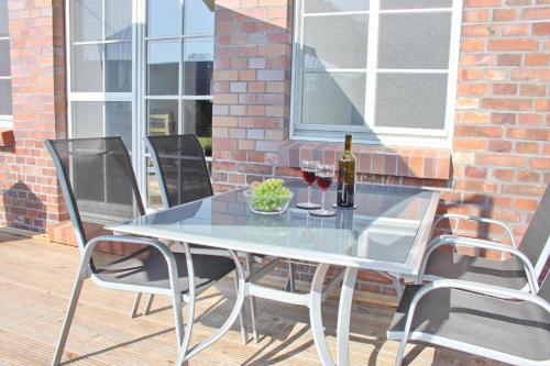 a glass table with two chairs and a bottle of wine at Hopkas Stall in Lübbenau