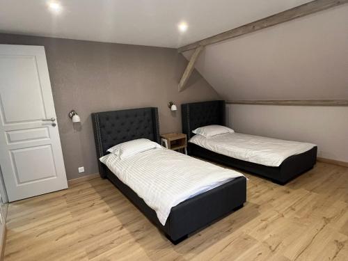 two beds in a room with a door and wooden floors at Gîte « Les Basse des Grouets » in Blois