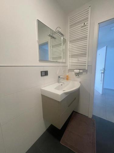 a white bathroom with a sink and a mirror at Joanna Apartment - MA City 2 in Mannheim
