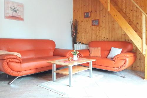 dwie pomarańczowe skórzane kanapy i stół w pokoju w obiekcie Ferienhaus Herz w mieście Lübbenau