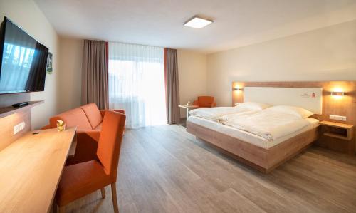 um quarto de hotel com uma cama, uma secretária e uma televisão em Gasthaus zum Stern em Gollhofen