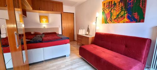 サンクト・ジョアン・イン・チロルにあるApartement GYARMATYのベッドルーム1室(ベッド1台、赤いソファ付)