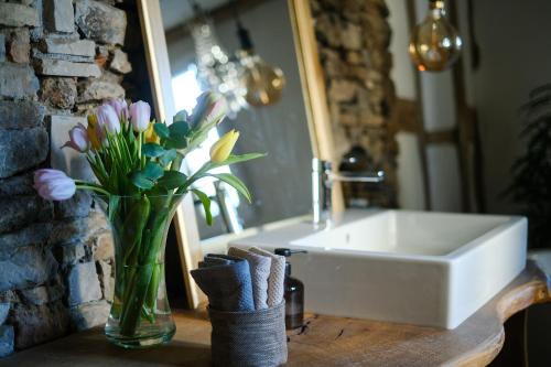 um vaso de flores em uma mesa ao lado de um lavatório em Ferienhaus Das Dömchen em Esch