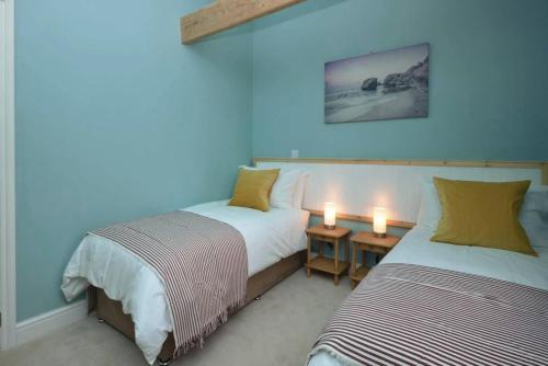 two beds in a room with blue walls and two candles at The Old Parlour in Frome