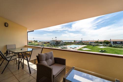 un balcone con tavolo, sedie e ampia finestra di Residence Primera a Moniga