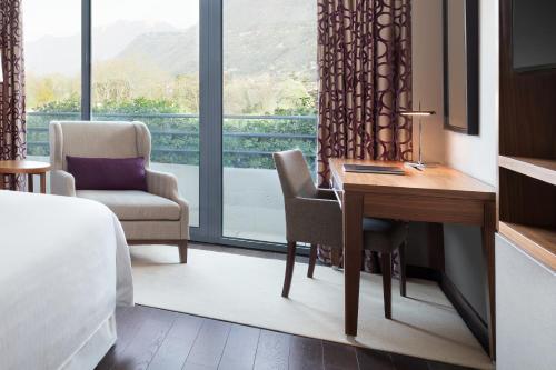 um quarto de hotel com uma secretária e uma grande janela em Sheraton Lake Como Hotel em Como