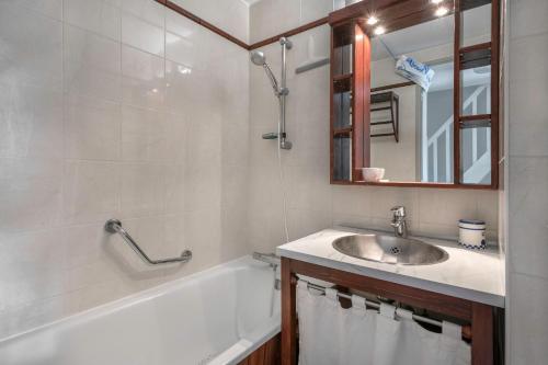 un bagno con un lavandino, una vasca e uno specchio di Appartement en résidence avec piscine a Batz-sur-Mer