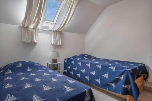 una camera con un letto con una copertina blu e una finestra di Appartement en résidence avec piscine a Batz-sur-Mer