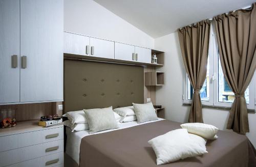 una camera da letto con un grande letto con cuscini bianchi di Camping Village Baia Azzurra Club a Castiglione della Pescaia