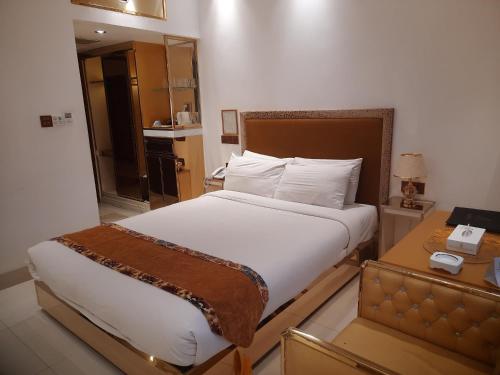a bedroom with a bed and a table with a telephone at Hotel Razmoni Isha Kha International in Dhaka