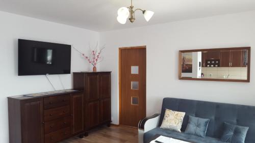 a living room with a couch and a flat screen tv at APARTHOTEL Apartamenty KORONA noclegi przy Termach Cieplickich 10proc rabatu do TERM Jelenia Góra Cieplice SELF CHECK IN in Jelenia Góra