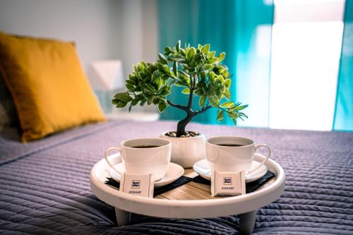 a tray with two cups and a potted plant on a bed at Turkusowe tarasy apartament in Czeladź