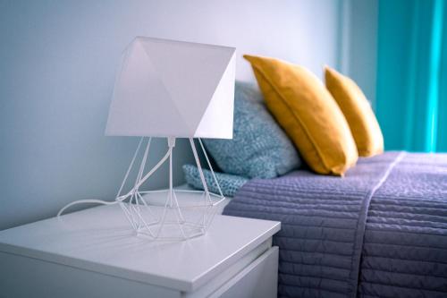 a white lamp on a table next to a bed at Turkusowe tarasy apartament in Czeladź