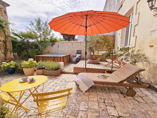 eine Terrasse mit einem Tisch und einem Sonnenschirm in der Unterkunft Sublime maison charentaise in Jarnac