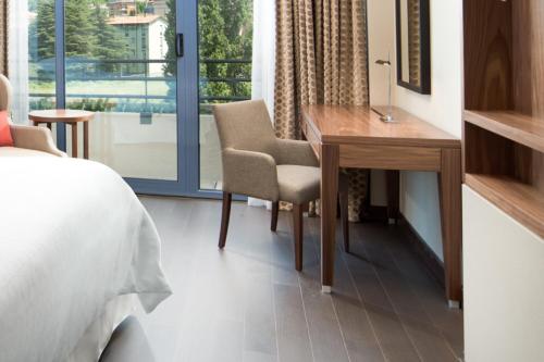 una camera da letto con scrivania, letto e finestra di Sheraton Lake Como Hotel a Como