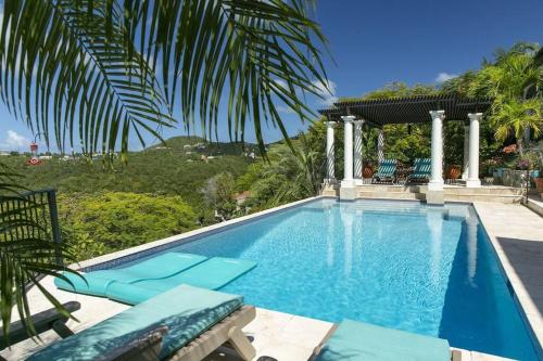 a swimming pool with blue chairs and a palm tree at Arc Du Soleil- 3 BDRM Sleeps 6 Stunning Views in Cruz Bay