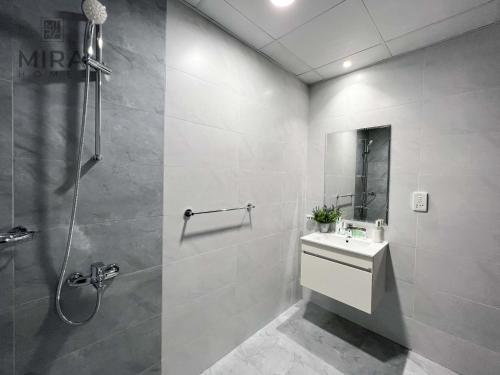 ein weißes Bad mit einer Dusche und einem Waschbecken in der Unterkunft Mira Holiday Homes - Serviced apartment in Dubai Land in Dubai