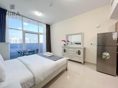 Mira Holiday Homes - Serviced apartment in Dubai Land في دبي: غرفة نوم بسرير ونافذة كبيرة