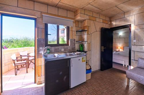 a kitchen with a sink and a balcony with a table at Anemomili Village in Kissamos