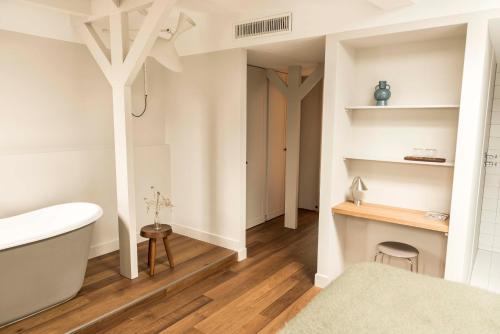 e bagno con pareti bianche, pavimenti in legno e vasca. di Boutique Hotel Weesp a Weesp