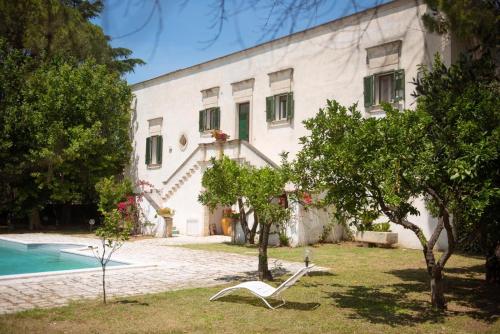 una casa bianca con piscina e alberi di Villa Encantamiento - Dimora Gelsomino - Masseria Storica nel cuore della Puglia con piscina a Latiano