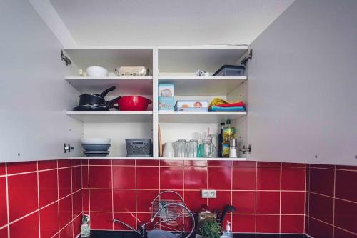 - une cuisine avec du carrelage rouge et des étagères blanches dans l'établissement Studio cosy proche centre-ville et gare, à Mulhouse