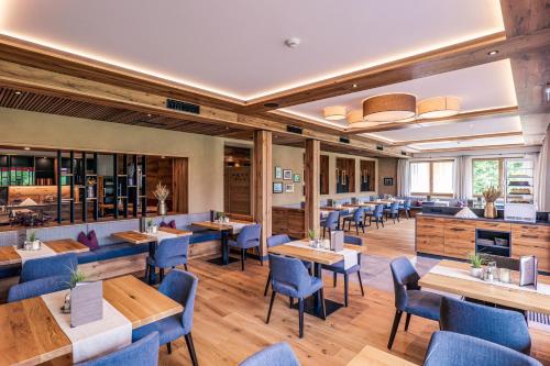 a restaurant with wooden tables and blue chairs at Hotel Föhrenhof in Stanzach