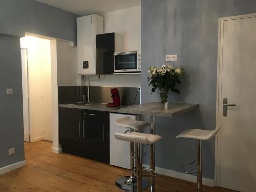 une cuisine avec un comptoir et des tabourets dans une pièce dans l'établissement Nid douillet, à Orchies