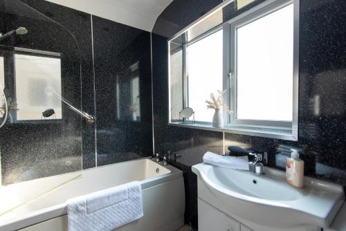 a bathroom with a bath tub and a sink and a window at Broome Road in Durham