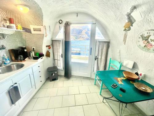 Mermaid Cave Apartment Old Port, Fira في فيرا: مطبخ بطاولة زرقاء ونافذة